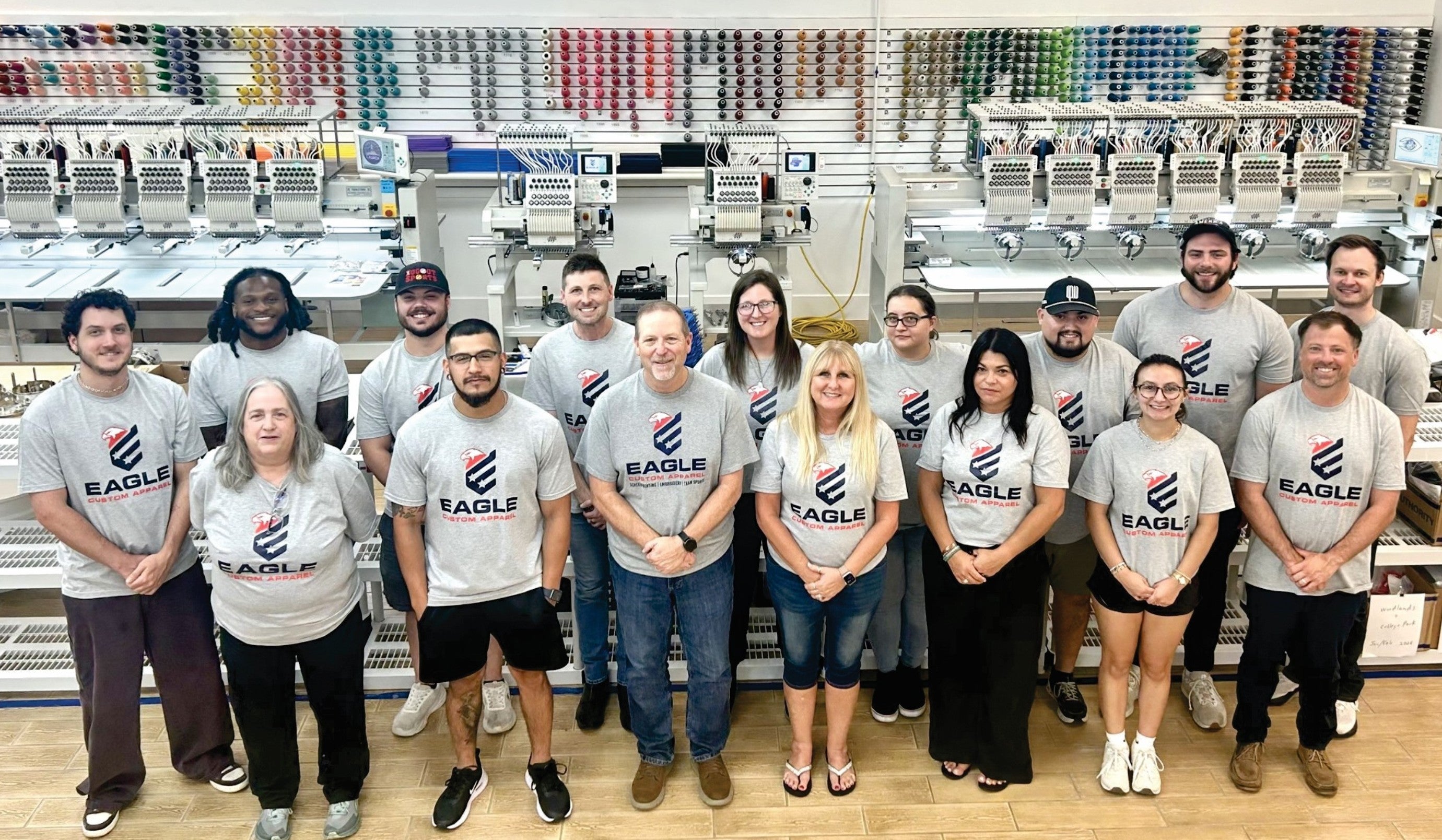 a staff photo in front of custom apparel printing machines