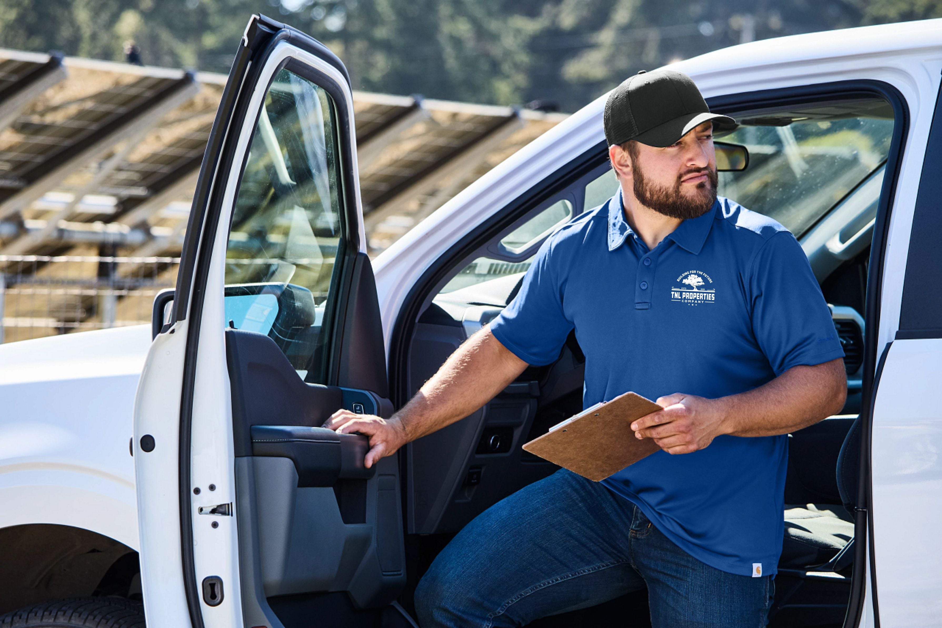 A man coming out of his truck in a blue polo shirt with branded logo on it