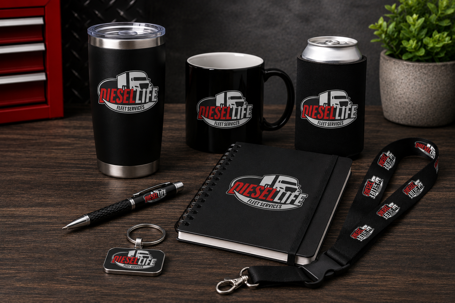 A coordinated branded merchandise set on a dark wood tabletop, including a black insulated tumbler, black mug, black can cooler, black notebook, pen, keychain, and lanyard, all printed with the DieselLife Auto Services logo.